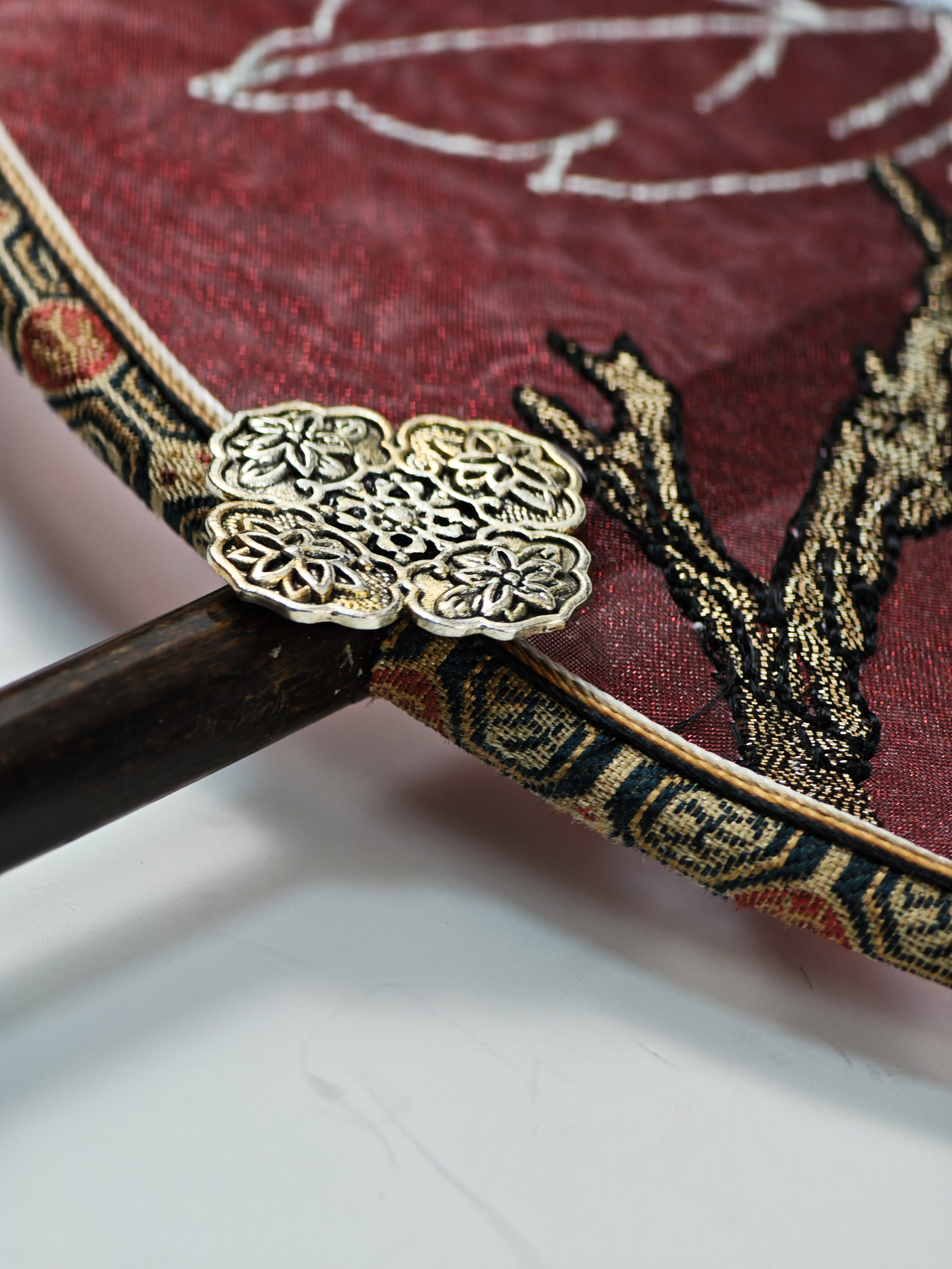 Dark wooden handle with carved metal connector detail on a cultural gift product